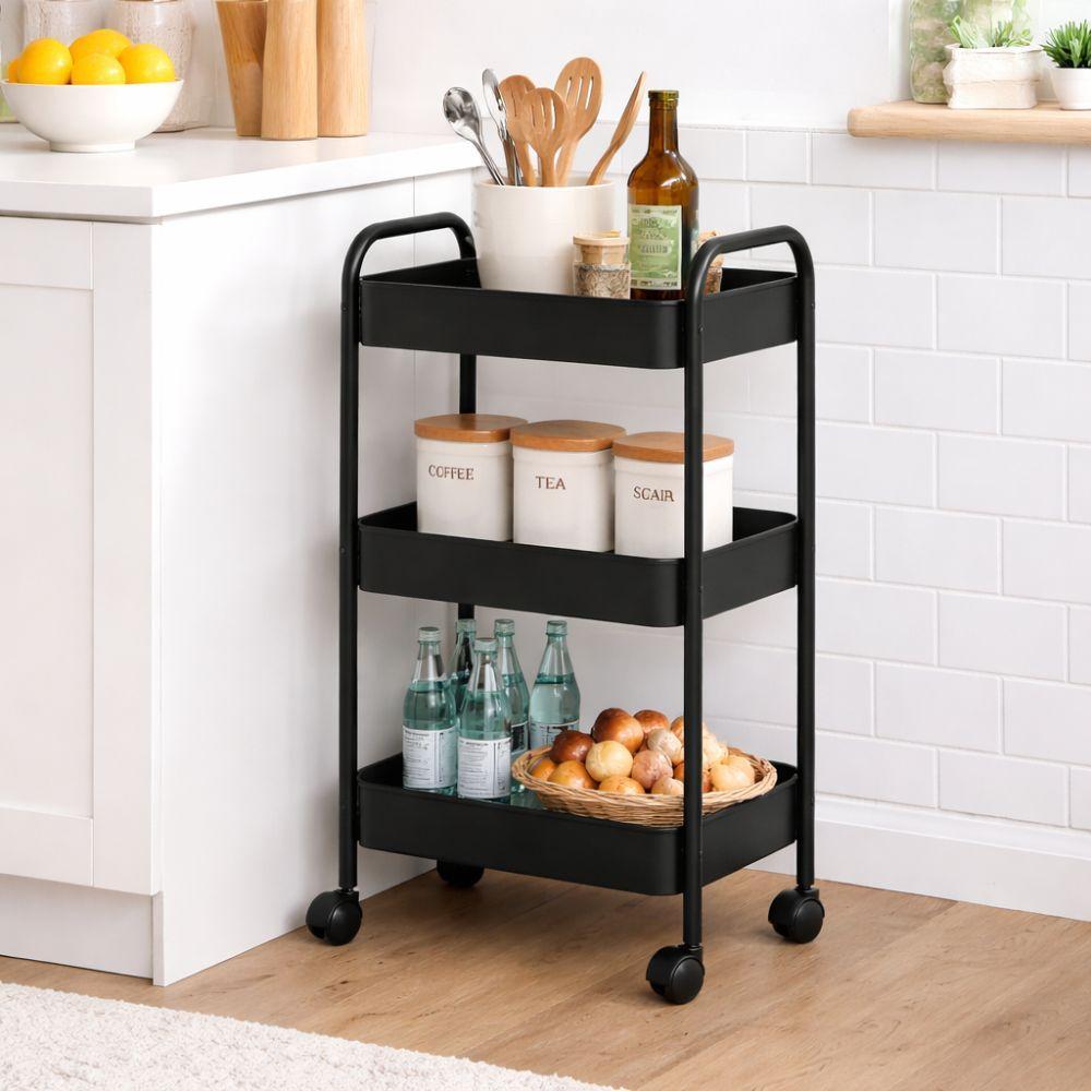 carrello multiuso salvaspazio a tre piani - foto 3 Carrello nero a tre ripiani in uso in cucina con bottiglie, arance e contenitori